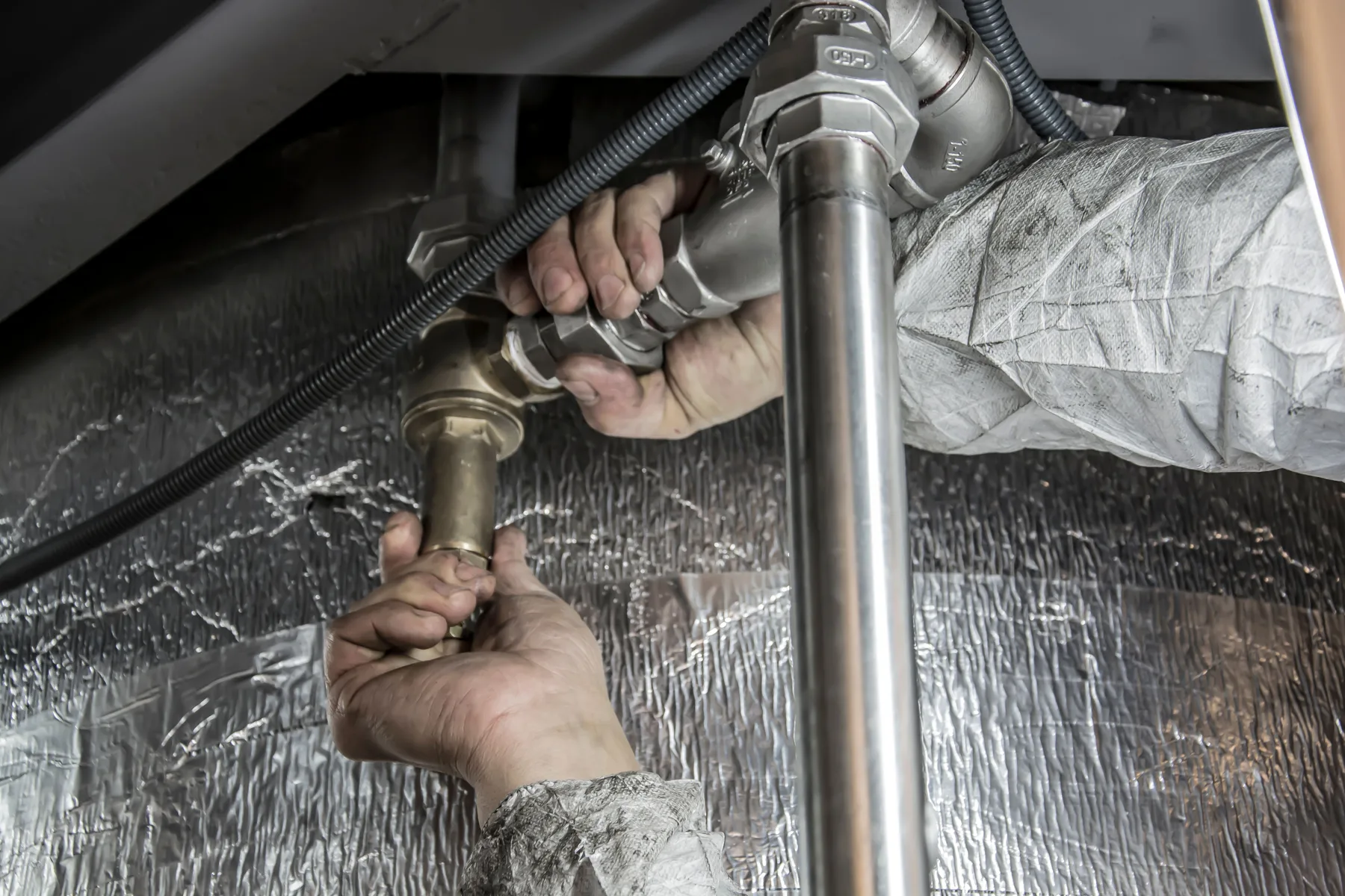 Stock photo of hands working on plumbing pipe fittings